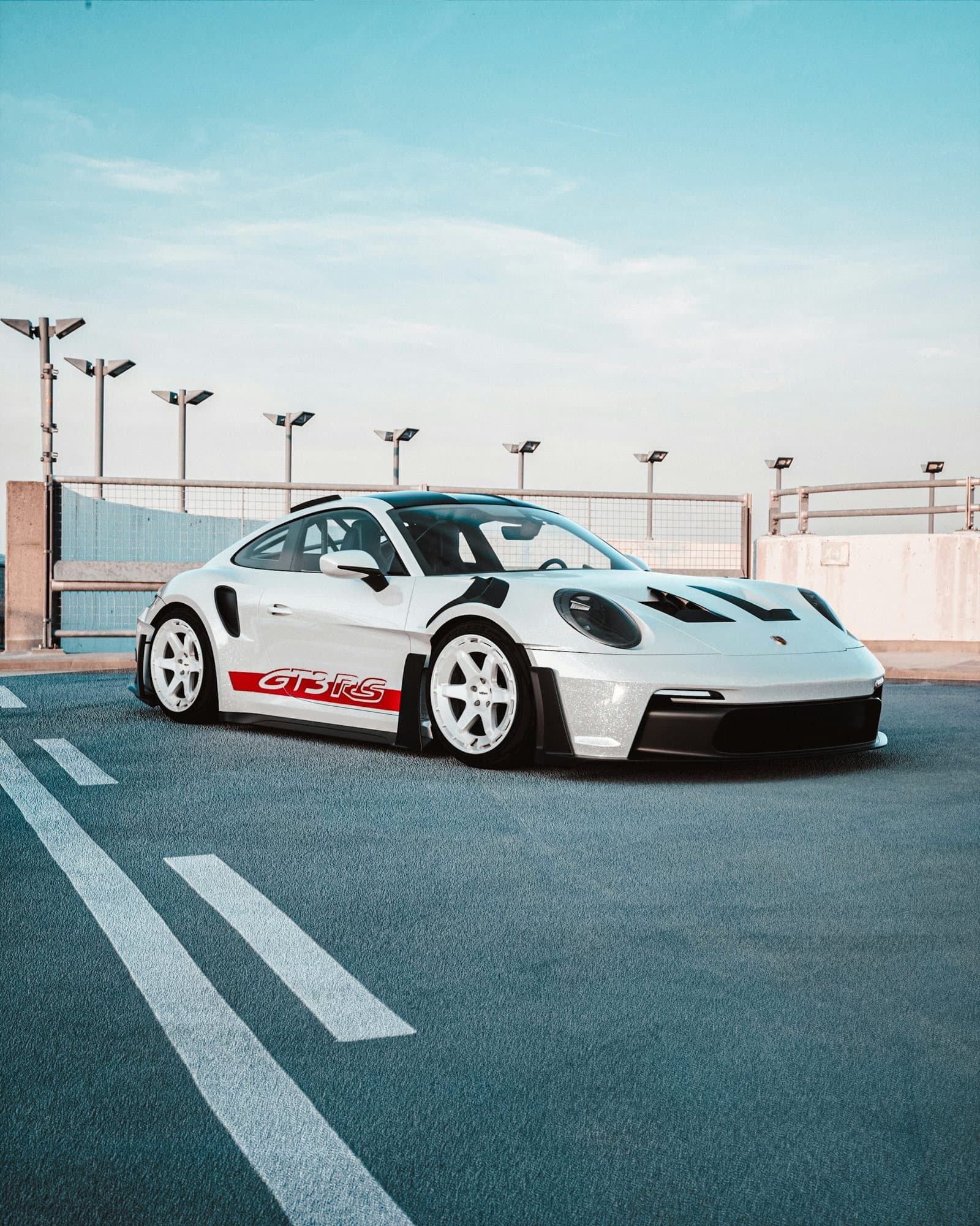 White Porsche GT3 RS with a red livery stripe and white wheels on a rooftop
