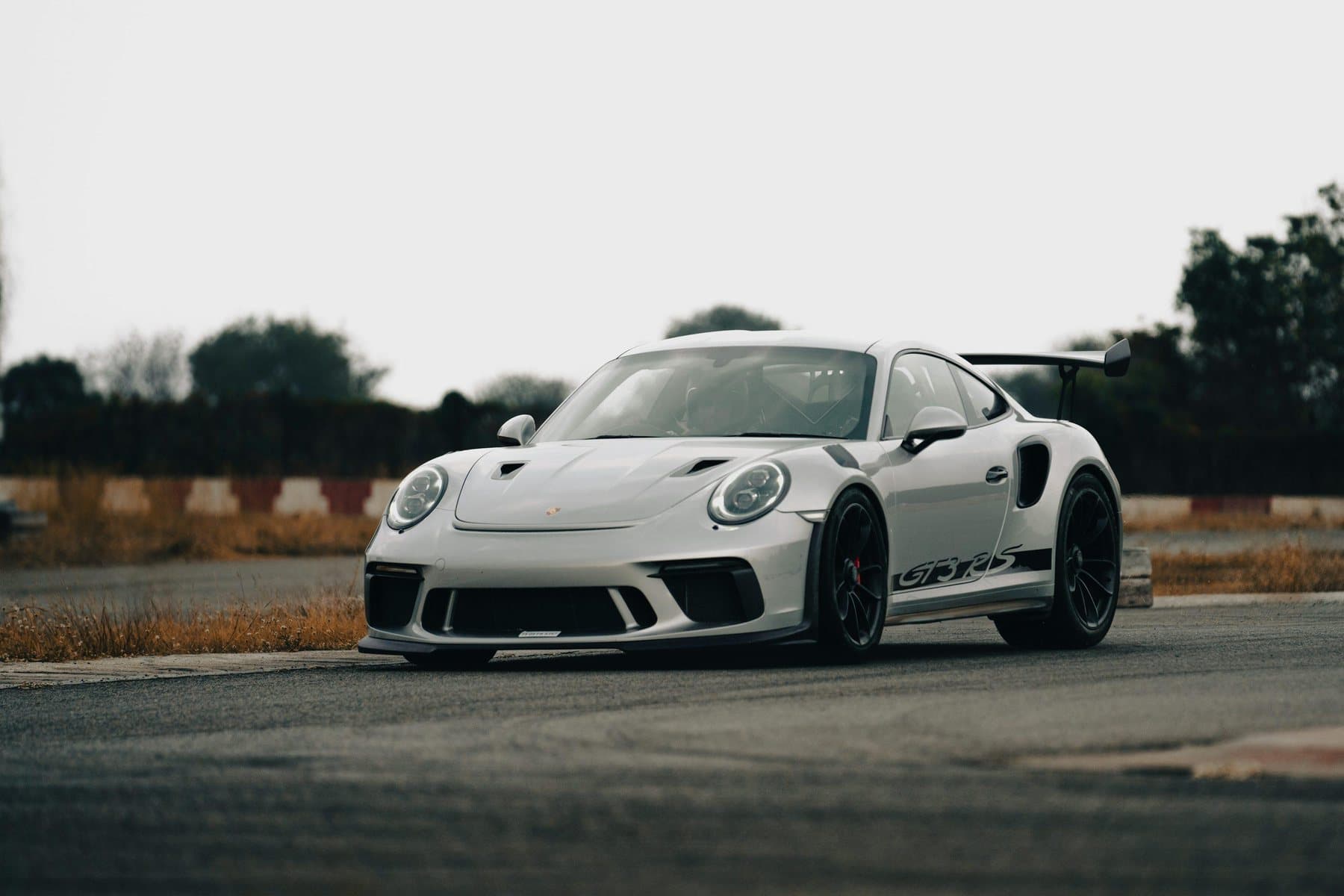 White Porsche GT3 RS with a livery stripe on a rooftop track apron