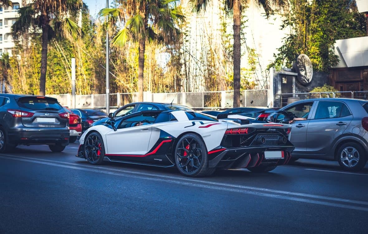 White and black Lamborghini Aventador SVJ rear three-quarter in traffic